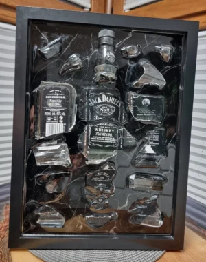 Rozbita butelka whisky elegancko zaprezentowana w pudełku z cieniem podkreślającym jej bogate kolory