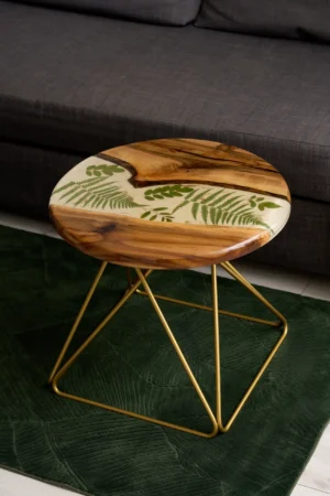Drewniany stolik kawowy z orzechowego drewna i liściem w żywicy, z elegancką złotą metalową podstawą