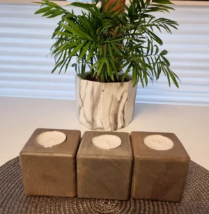 Zestaw trzech drewnianych świeczników w subtelnym odcieniu szarości, wprowadzający naturalny urok.