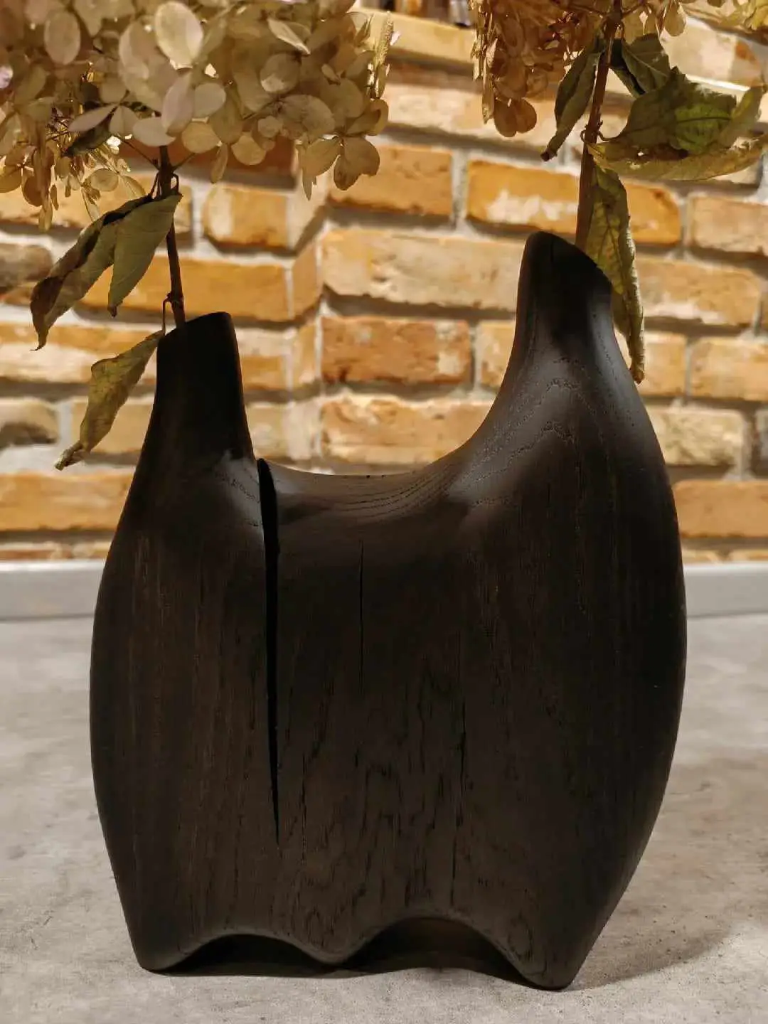 Elegancki czarny wazon z dębu z bukietem kwiatów, prezentujący się na neutralnym tle.