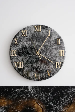 Czarno-biały zegar z cyframi rzymskimi, zaprojektowany z eleganckim wykończeniem z żywicy w kolorze czarnym i złotym