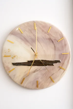 Okrągły zegar ścienny wykonany z żywicy epoksydowej o marmurkowym wzorze w odcieniach beżu i fioletu, z dekoracyjnym drewnianym akcentem i złotymi wskazówkami