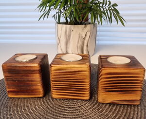 Trzy kwadratowe świeczniki z opalanego dębu, przeznaczone na świece typu "tea light".