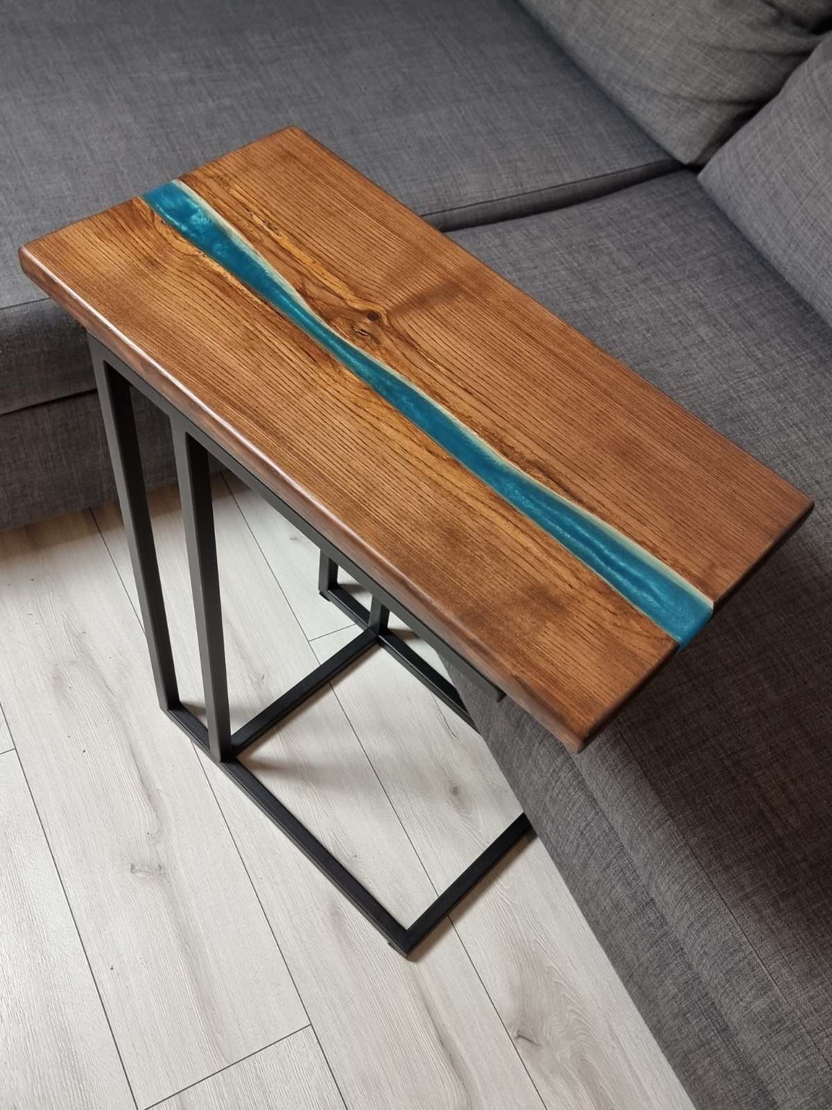 Stolik wsuwany pod sofe z brązowegro drewna i turkusowej żywicy
